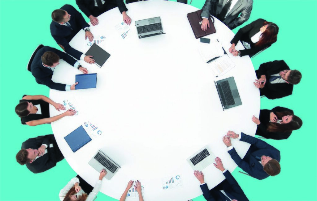 Ihmisiä pöydän ympärillä ylhäältä päin.