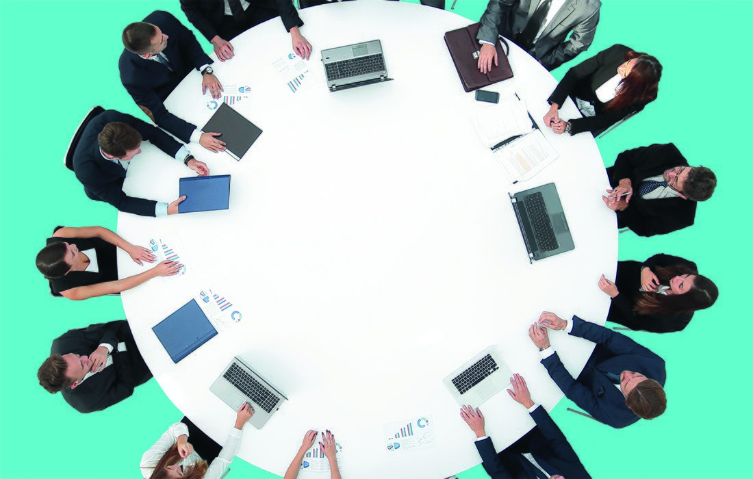 Ihmisiä pöydän ympärillä ylhäältä päin.